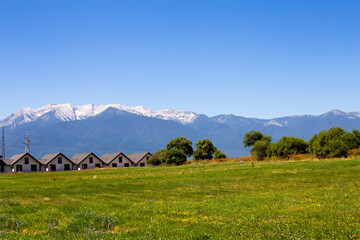 Fototapeta na wymiar Panoramic view of houses against the backdrop of mountains and a meadow with wildflowers in Bulgaria
