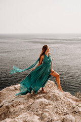 Woman sea green dress. Side view a happy woman with long hair in a long mint dress posing on a beach with calm sea bokeh lights on sunny day. Girl on the nature on blue sky background.