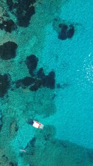 Fototapeta na wymiar Aerial view of a boat in crystal clear blue ocean waters of Corfu Island in Greece.