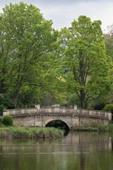 A stone bridge over a lake in the UK countryside.