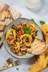 cooked mussels with parsley and lemon in white bowl, top view