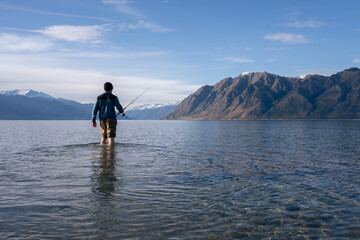 Trout fisherman at a lake with mountains in New Zealand
