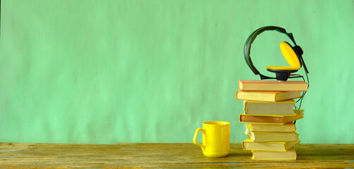 audio book concept with stack of books and vintage headphones on pastel green paint background,good...