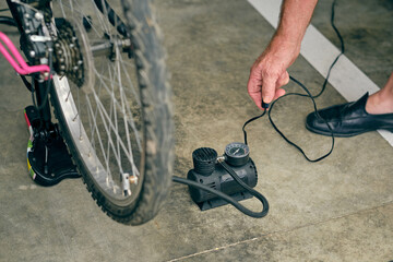 Old man inflating bicycle with compressor in garage