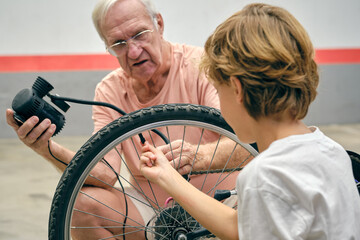 Little child with grandfather pumping bicycle tyre