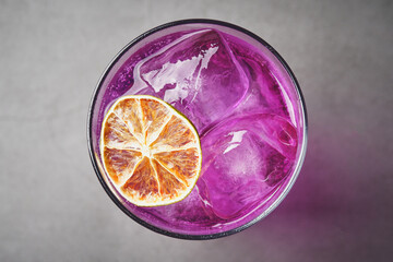 Refreshing drink with purple ice with dehydrated orange slice