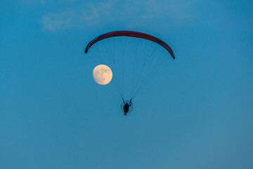 paragliding on blue sky with full moon