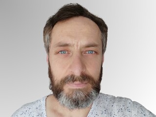 A bearded, blue-eyed, middle-aged, handsome white man with blue eyes poses in various ways.