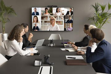 Cheerful mature business mentor woman training diverse office staff on video conference chat,...