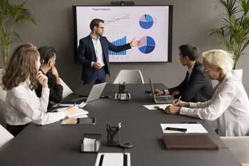 Confident young business leader man presenting marketing statistic report to partners, investors,...