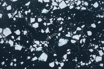 Drone shot of a ship cruising through sea ice in Svalbard