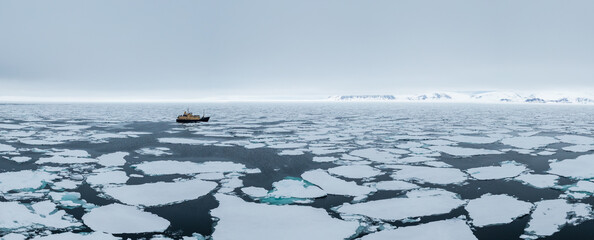 Drone shot of a ship cruising through sea ice in Svalbard