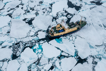 Drone shot of a ship cruising through sea ice in Svalbard