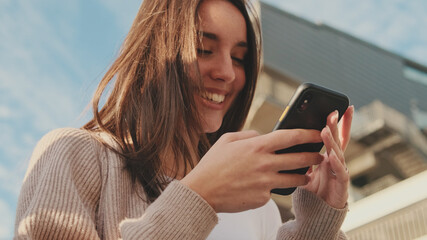 Close-up of a young woman using a mobile phone. Portrait of a happy girl typing a social media...