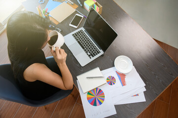 Female office worker take a coffee break while working with laptop in office room