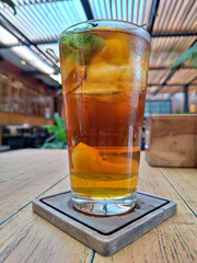 A glass of iced peach tea at the top of a wooden table