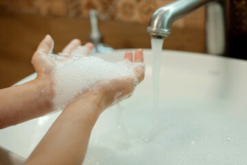 Little girl washing hands with water and soap in bathroom. Hands hygiene and virus infections prevention