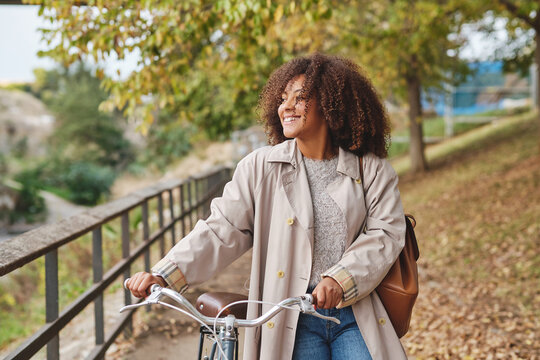 Positive black woman with bicycle in park