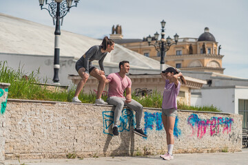 Two friends joking with their female friend in a grey outfit. She is smiling