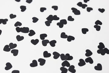 black heart shaped confetti on a white paper background
