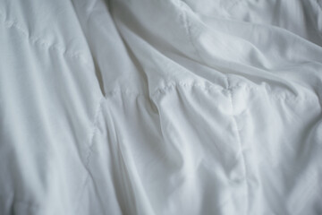 Closeup of beautiful white shiny crumpled  fabric sheets on the bed