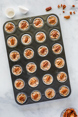 A pan of homemade sweet salted caramel pecan tartlets.