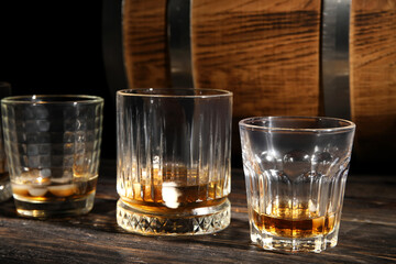 Glasses of cold whiskey on dark wooden background