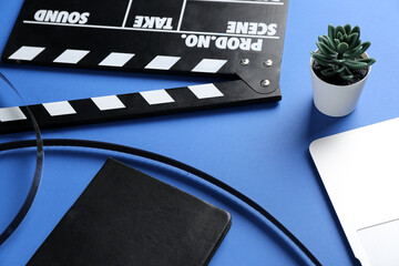 Fototapeta na wymiar Notebook with film and movie clapper on blue background, closeup