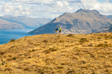 Mature hikers standing on grassland enjoying beautiful scenery