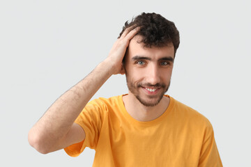 Fototapeta na wymiar Young brunette man with stylish hairdo on light background, closeup