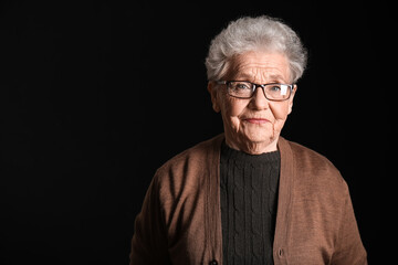 Senior woman in eyeglasses on black background, closeup