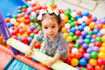 Fototapeta premium Cute toddler playing in the ball pit of the playground