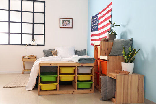 Interior of children's bedroom with cozy bed, USA flag and shelving units