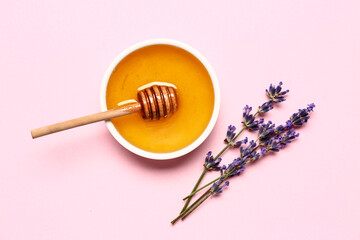 Bowl of sweet lavender honey, dipper and flowers on pink background