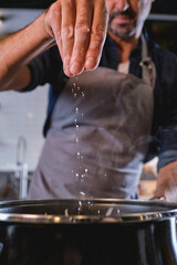 Person adding salt into saucepan