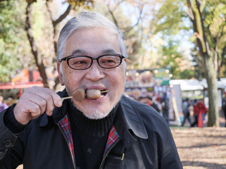 An asian man in glasses eating dango - 629245315