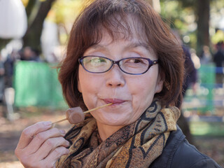 An older Japanese woman eating dango