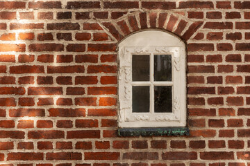 Red brick wall with white arched window
