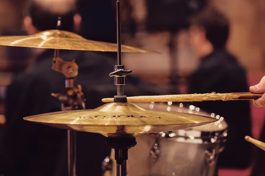 Drummer performing on a drum set, striking the drums and cymbals with sticks.