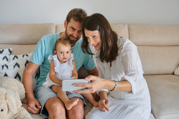 Obraz premium Parents with daughter watching smartphone at home