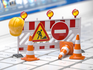 Web site under construction concept. Traffic barrier and cones on a laptop keyboard.