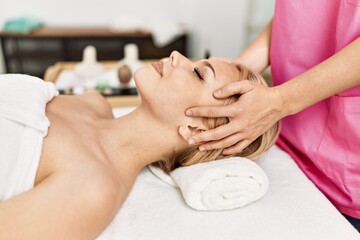 Young caucasian woman lying on table having head massage at beauty salon