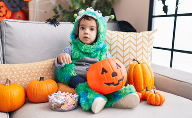 Adorable hispanic boy having halloween party holding sweets at home