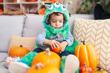 Fototapeta premium Adorable hispanic boy having halloween party holding pumpkin basket at home