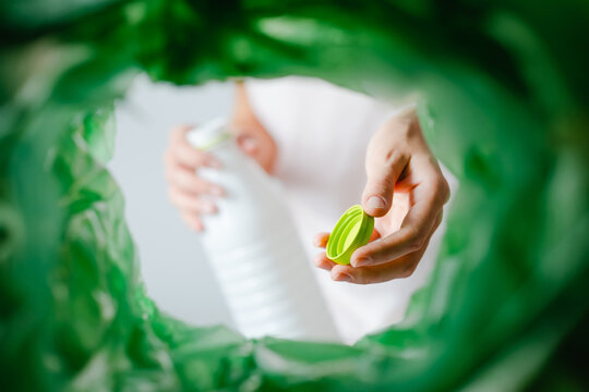 Low Angle View Female Sorting Packaging Bottle Recycling Bin POV. A Hand Putting A Green Cork From A Bottle Into A Container. Waste Segregation, Waste Sorting, Waste Recycle. 