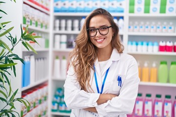 Young beautiful hispanic woman pharmacist smiling confident standing with arms crossed gesture at...