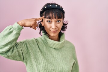 Young beautiful woman standing over pink background smiling pointing to head with one finger, great idea or thought, good memory