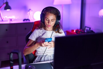 Young beautiful hispanic woman streamer using computer and smartphone at gaming room