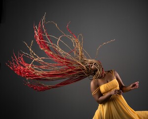 African American female wearing a bright yellow dress with her long red hair blowing in the wind