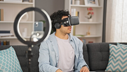 Young latin man recording video tutorial playing with virtual reality glasses at home